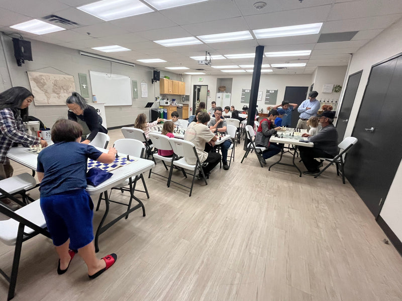 A coach helping kids at the chess boards